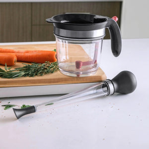 Baster on counter next to a measuring pot and carrots on a cutting board.