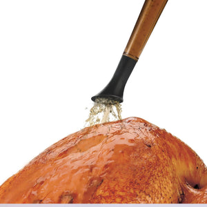 Baster applying juice to a turkey with the black "shower head" attachment