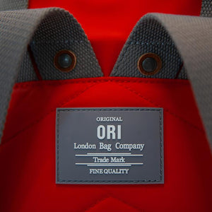 Close up on gray back label of red ORI bag reads "Original ORI London Bag Company, Trade Mark, Fine Quality" in white