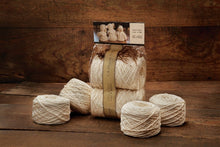 Load image into Gallery viewer, Balls of white yarn with package showing three babies in knitted wear from yarn